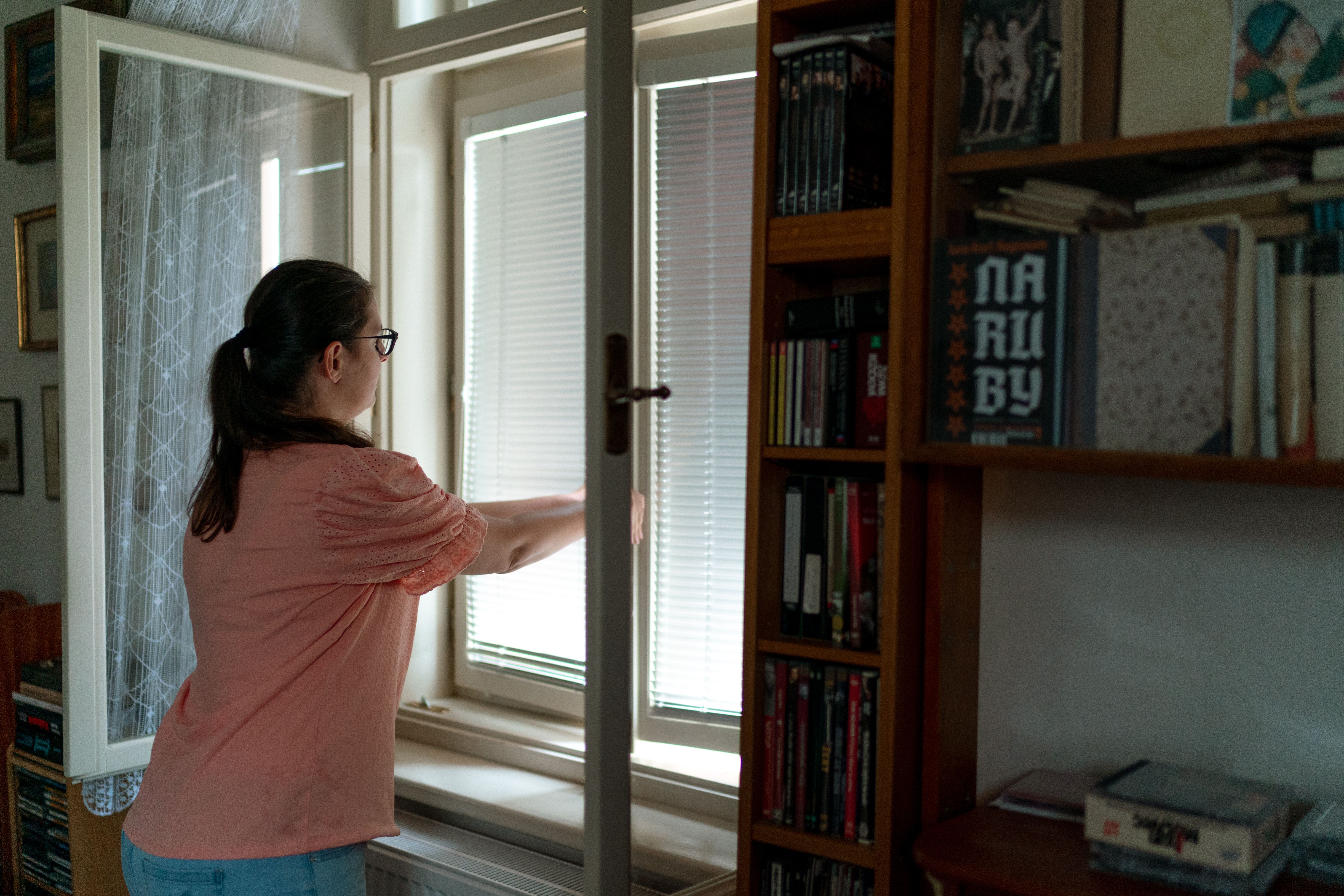 A homeowner ventilating a room to tackle condensation, with a damp meter nearby